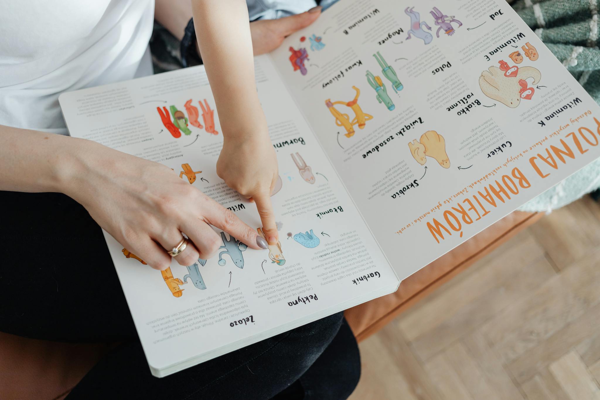 A child and adult engaging with an educational book, pointing to illustrations.